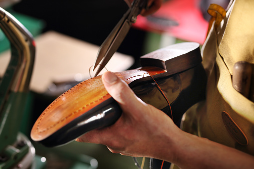 man cutting thread on a shoe